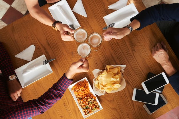 Foto gratuita vista superior de personas recortadas brindando por amistad con cerveza