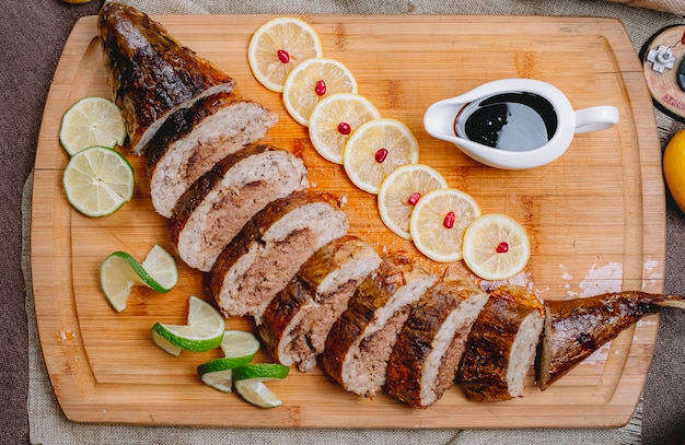 Foto gratuita vista superior pescado al horno relleno de lavangi y rodajas de lima y limón en un tablero