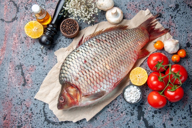 Foto gratuita vista superior de pescado crudo fresco con tomates rojos sobre fondo azul.