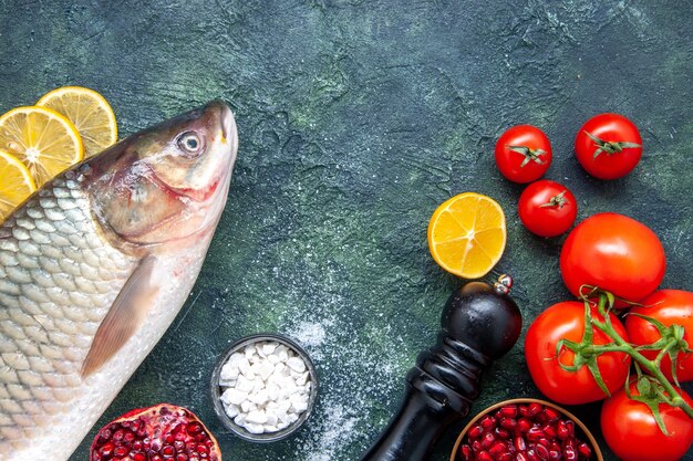 Vista superior de pescado fresco tomates molinillo de pimienta rodajas de limón en la mesa de la cocina