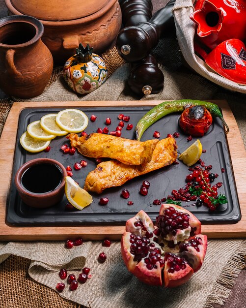 Vista superior pescado frito con rodajas de granada ‹limón y verduras a la plancha con salsa de granada