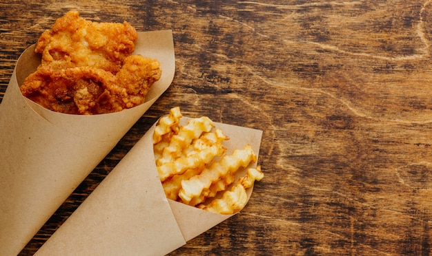 Vista superior de pescado y patatas fritas en una envoltura de papel con espacio de copia