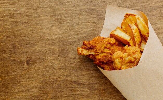 Vista superior de pescado y patatas fritas en una envoltura de papel con espacio de copia