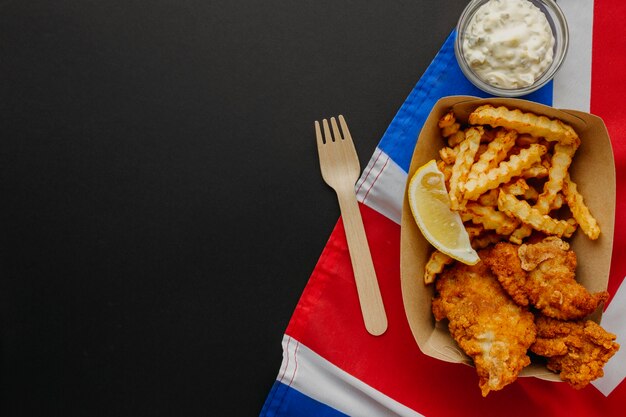 Vista superior de pescado y patatas fritas con espacio de copia y bandera de gran bretaña