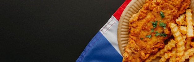 Vista superior de pescado y patatas fritas en un plato con la bandera de gran bretaña y espacio de copia