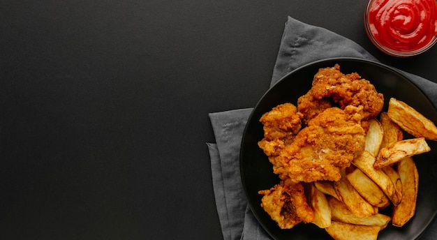 Vista superior de pescado y patatas fritas en un plato con espacio de copia