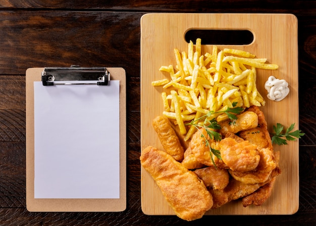 Vista superior de pescado y patatas fritas con portapapeles