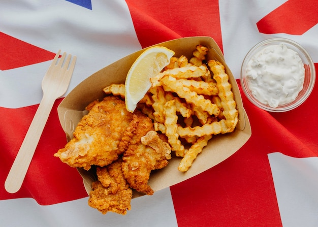 Foto gratuita vista superior de pescado y patatas fritas con rodaja de limón y bandera de gran bretaña