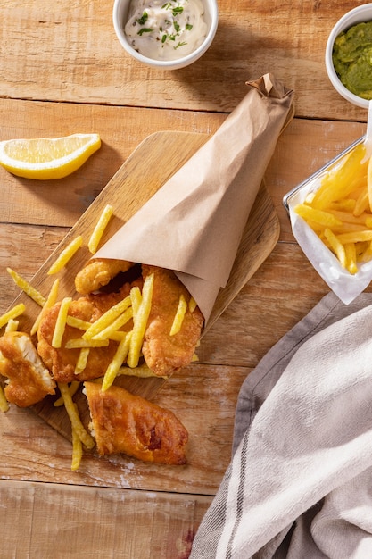 Vista superior de pescado y patatas fritas con salsas