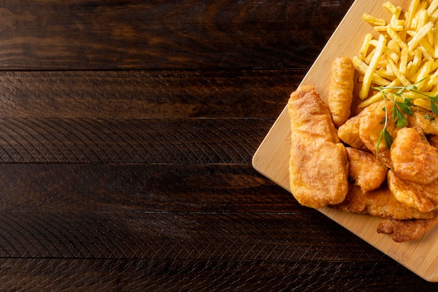 Vista superior de pescado y patatas fritas en una tabla de cortar con espacio de copia