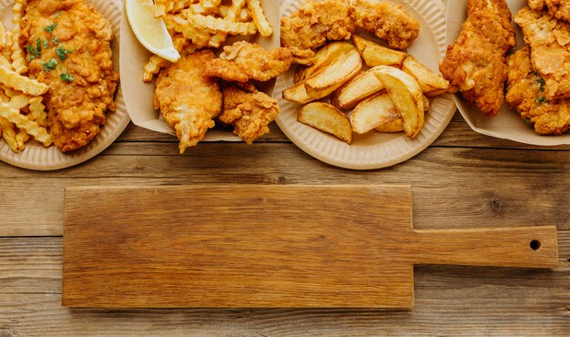 Vista superior de pescado y patatas fritas con tabla de cortar