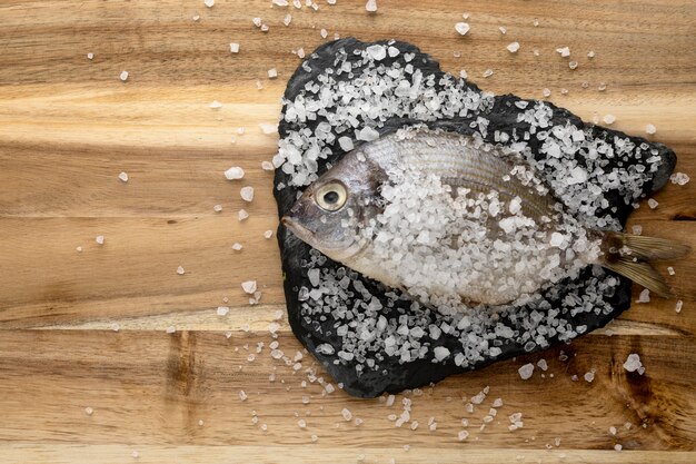 Vista superior de pescado en pizarra con sal