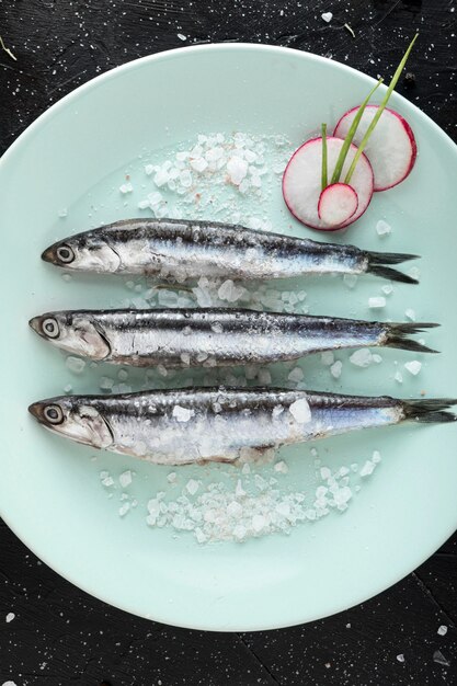 Vista superior de pescado en plato con sal y rábano