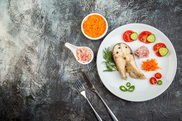 Vista superior de pescados crudos y alimentos frescos picados de pimienta en un plato blanco y cubiertos en la superficie del hielo