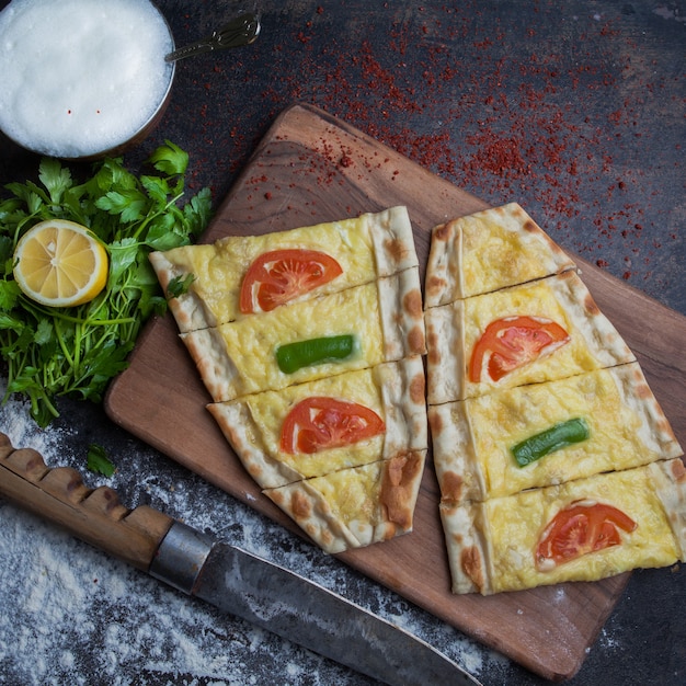 Foto gratuita vista superior pide con queso y perejil y limón y ayran en tabla de cortar