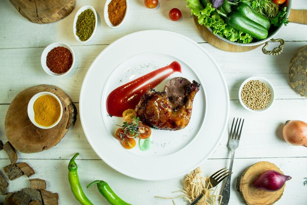 Vista superior de pierna de pollo asado con tomates cherry y salsa de tomate en un plato blanco