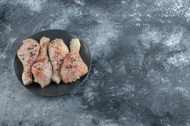 Foto gratuita vista superior de las piernas de pollo crudo marinado en placa negra.