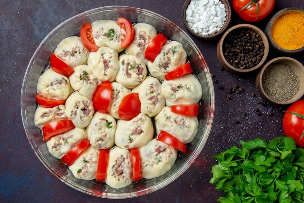 Vista superior de piezas de masa cruda con tomates de carne molida y condimentos en comida oscura plato de ensalada de cocina comida de color de foto