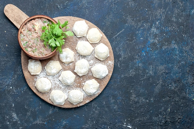 Foto gratuita vista superior de piezas de masa enharinada con verduras de carne picada en el escritorio oscuro, comida de masa, carne cruda, cena, pastelería