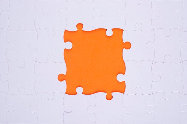 Vista superior de piezas de rompecabezas blancas y fondo naranja