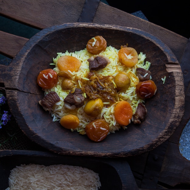 Vista superior pilaf con frutos secos y secas y hojas de castaño y arroz y romero en placa de madera