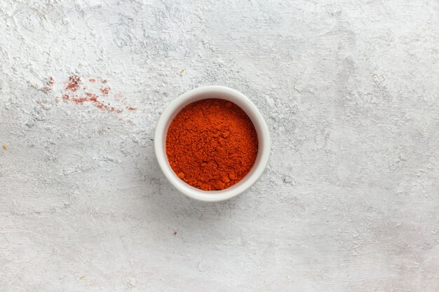 Vista superior de la pimienta molida de color naranja en el escritorio blanco ingrediente de pimienta producto especia de alimentos caliente