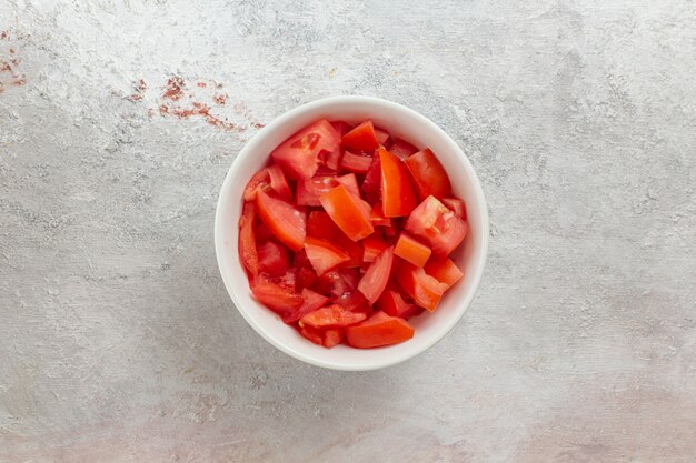 Vista superior de pimiento rojo en rodajas dentro de una pequeña olla en la superficie blanca ensalada de verduras comida cruda comida salud