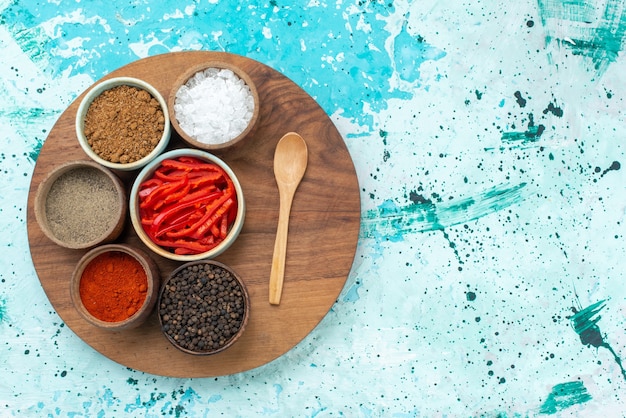 Foto gratuita vista superior de pimiento rojo en rodajas con sal pimienta y otros condimentos en el color de ingrediente de sal pimienta de escritorio azul claro