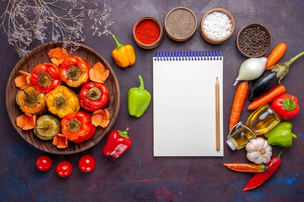 Vista superior de pimientos cocidos con verduras frescas y condimentos en la mesa gris comida dolma verduras carne de res