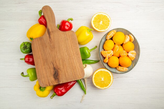 Vista superior de pimientos frescos con mandarinas en la dieta de ensalada de escritorio blanco foto de color maduro vida sana