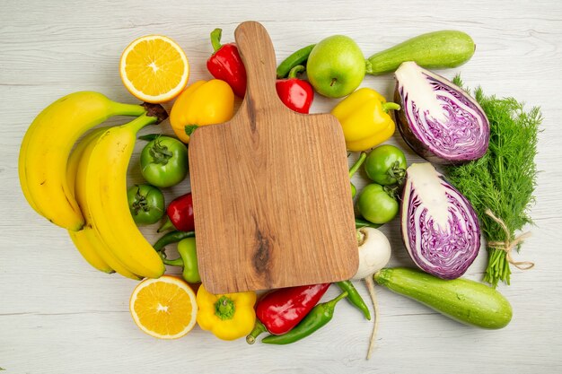 Vista superior de pimientos frescos con manzanas, plátanos y repollo rojo sobre fondo blanco ensalada de dieta de vida saludable de color maduro