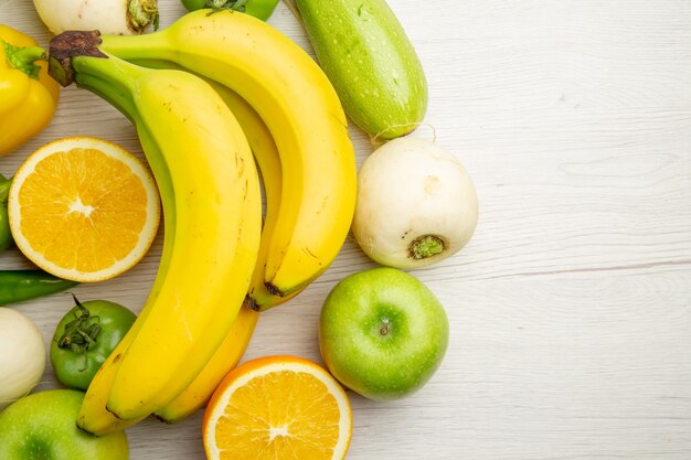 Vista superior de pimientos frescos con plátanos y manzanas sobre fondo blanco, ensalada, vida sana, dieta de color maduro