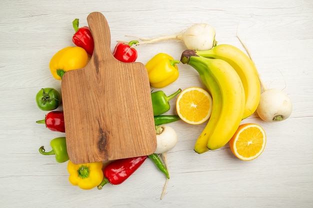 Vista superior de pimientos frescos con plátanos y naranja sobre un fondo blanco, ensalada, vida sana, dieta de color maduro