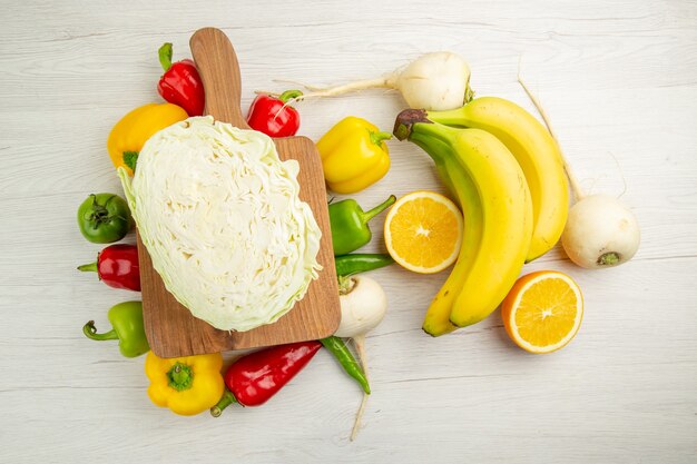 Vista superior de pimientos frescos con plátanos y naranja sobre fondo blanco, ensalada, vida sana, foto, dieta de color maduro