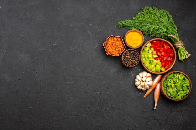 Vista superior de pimientos morrones en rodajas con verduras y condimentos en la superficie oscura producto comida comida ensalada salud