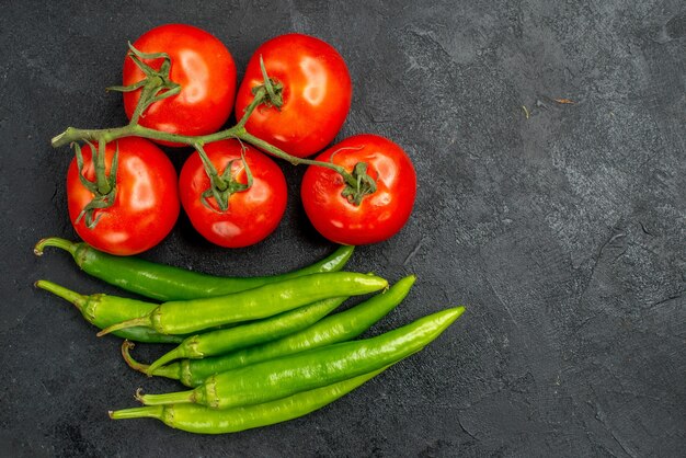 Vista superior de pimientos picantes verdes con tomates rojos