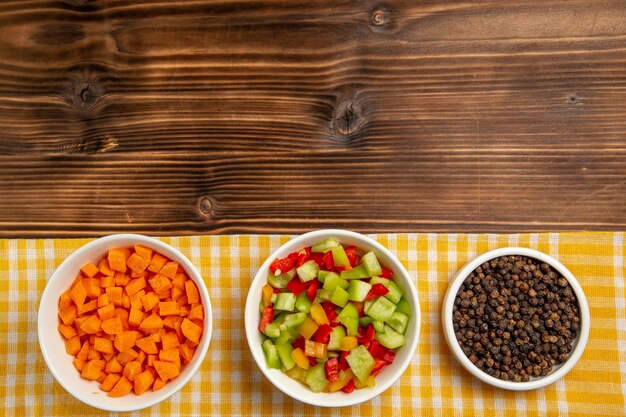 Vista superior de pimientos en rodajas con condimentos en la mesa de madera marrón comida vegetal ensalada saludable