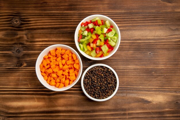 Vista superior de pimientos en rodajas con condimentos en una mesa de madera marrón, verduras, comida, ensalada saludable