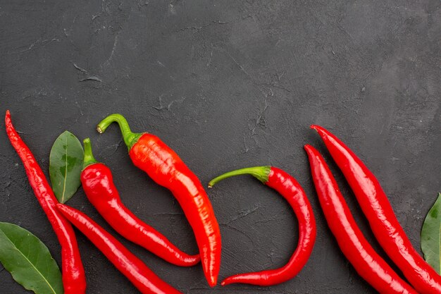 Vista superior de pimientos rojos y hojas de pago en mesa negra con espacio de copia