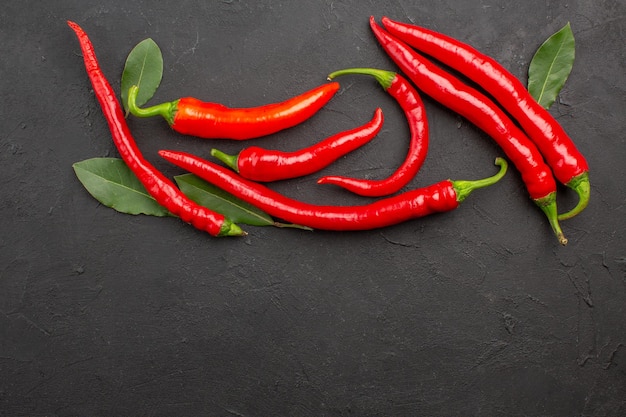 Vista superior de pimientos rojos y hojas de pago sobre suelo negro con espacio libre