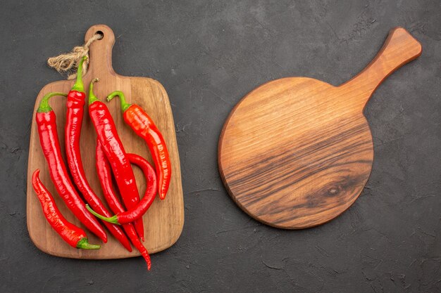 Vista superior de pimientos rojos en una tabla de cortar y una tabla de cortar ovalada en la mesa negra con espacio de copia