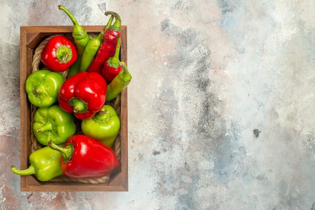 Vista superior de pimientos rojos y verdes pimientos picantes en caja de madera en lugar libre de superficie desnuda