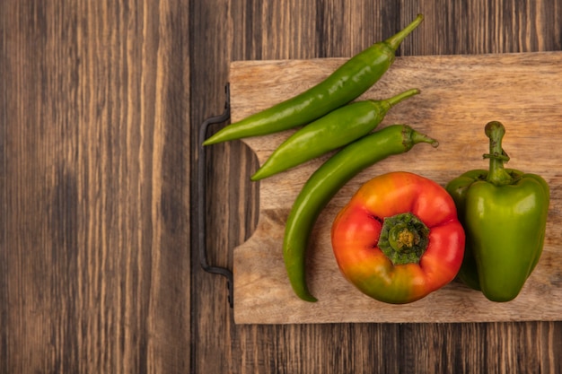 Vista superior de pimientos rojos y verdes saludables en una tabla de cocina de madera sobre una superficie de madera con espacio de copia