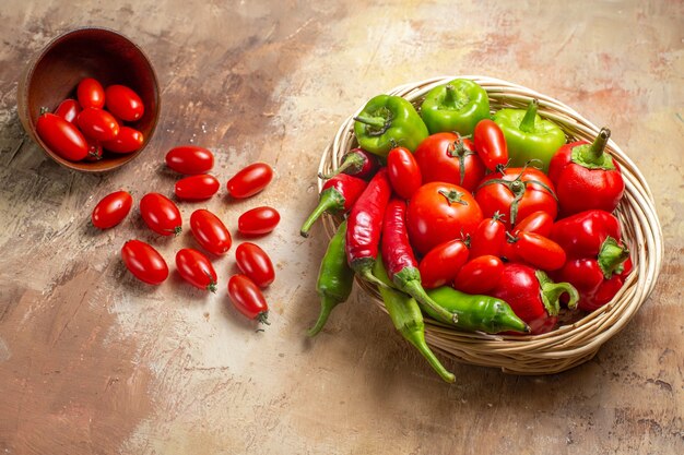 Vista superior de pimientos verdes y rojos pimientos picantes tomates en cesta de mimbre tomates cherry esparcidos del tazón sobre fondo ámbar