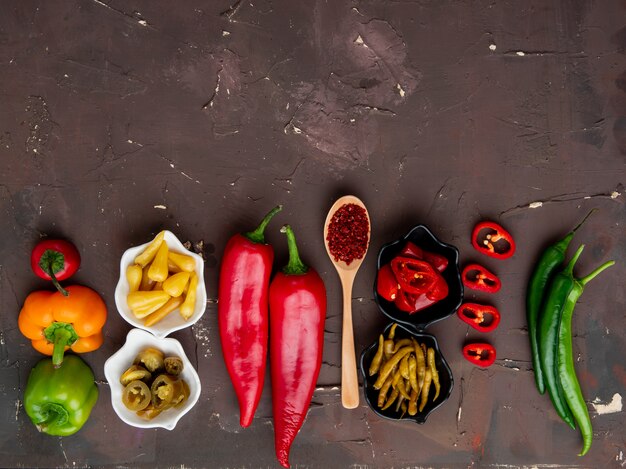 Vista superior de pimientos con zumaque y pimientos salados sobre fondo marrón con espacio de copia