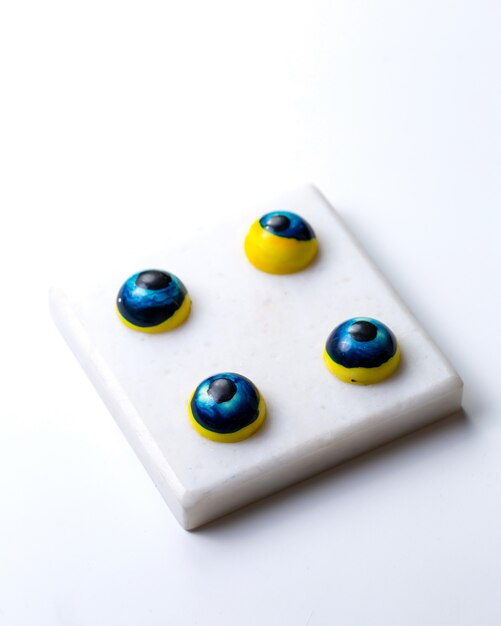 Vista superior pintada de ojos azules en forma de dulces de chocolate en soporte blanco