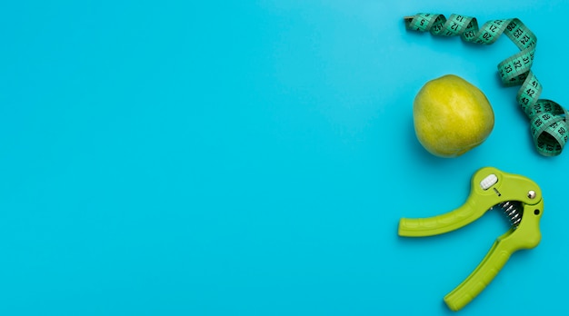 Foto gratuita vista superior de la pinza de mano con manzana y cinta métrica