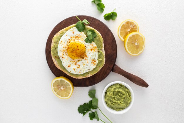 Vista superior de pita con aguacate y huevo frito en tabla de cortar