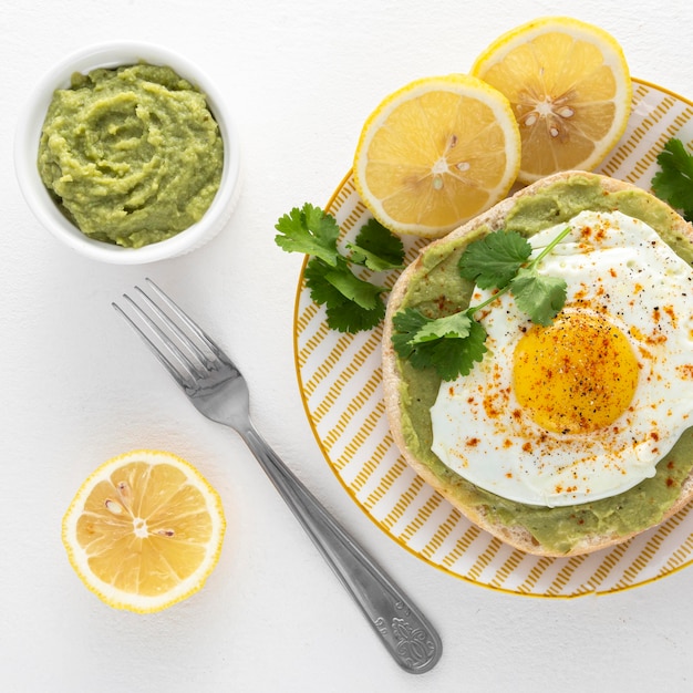 Vista superior de pita con untar de aguacate y huevo frito en un plato con un tenedor