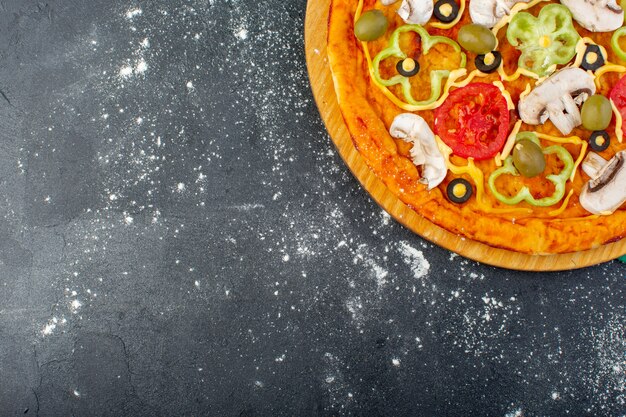 Vista superior de la pizza de champiñones con tomates, aceitunas, champiñones, todos en rodajas por dentro con aceite en el escritorio gris, masa de pizza, comida italiana